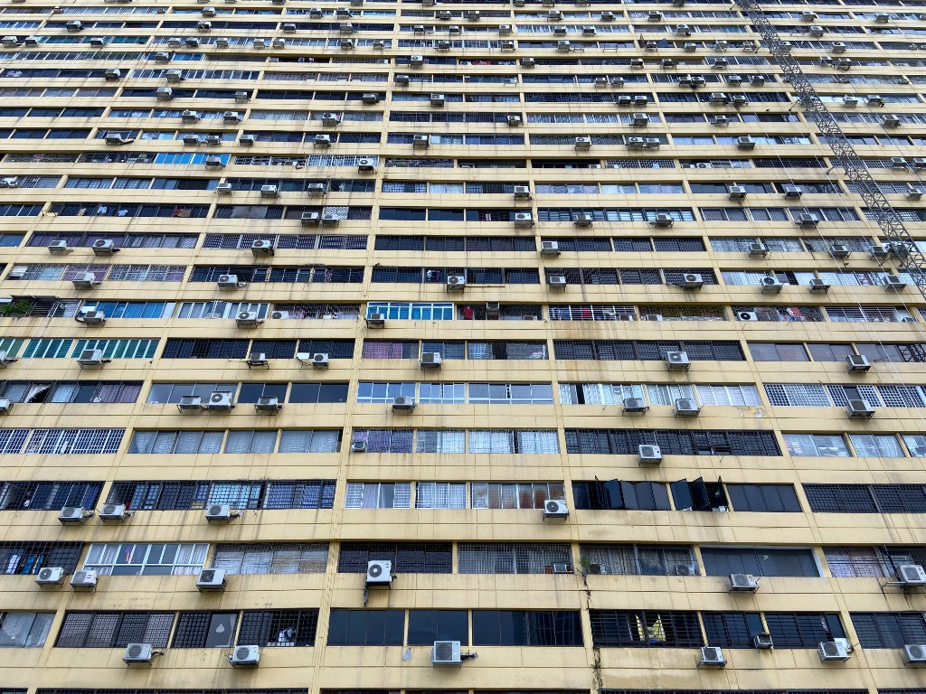 Yellow residential tower covered with window air conditioners