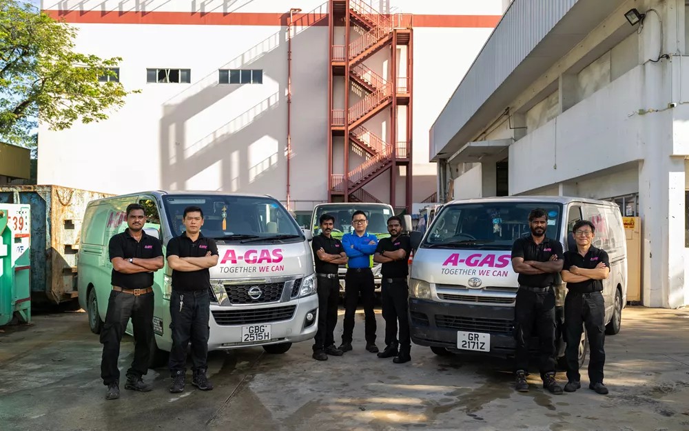 A-Gas team members in front of branded service vans at a Singapore industrial facility